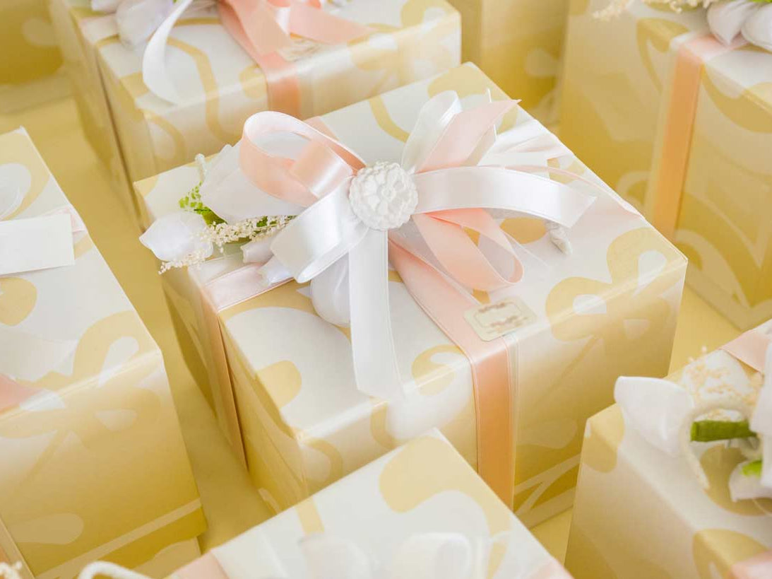 Elegant wedding gifts wrapped in cream and gold paper, finished with pink and white satin ribbons and floral embellishments