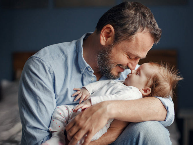 A father holding his baby close in a quiet moment at home — a tender reflection of new dad experiences and bonding during the first year.